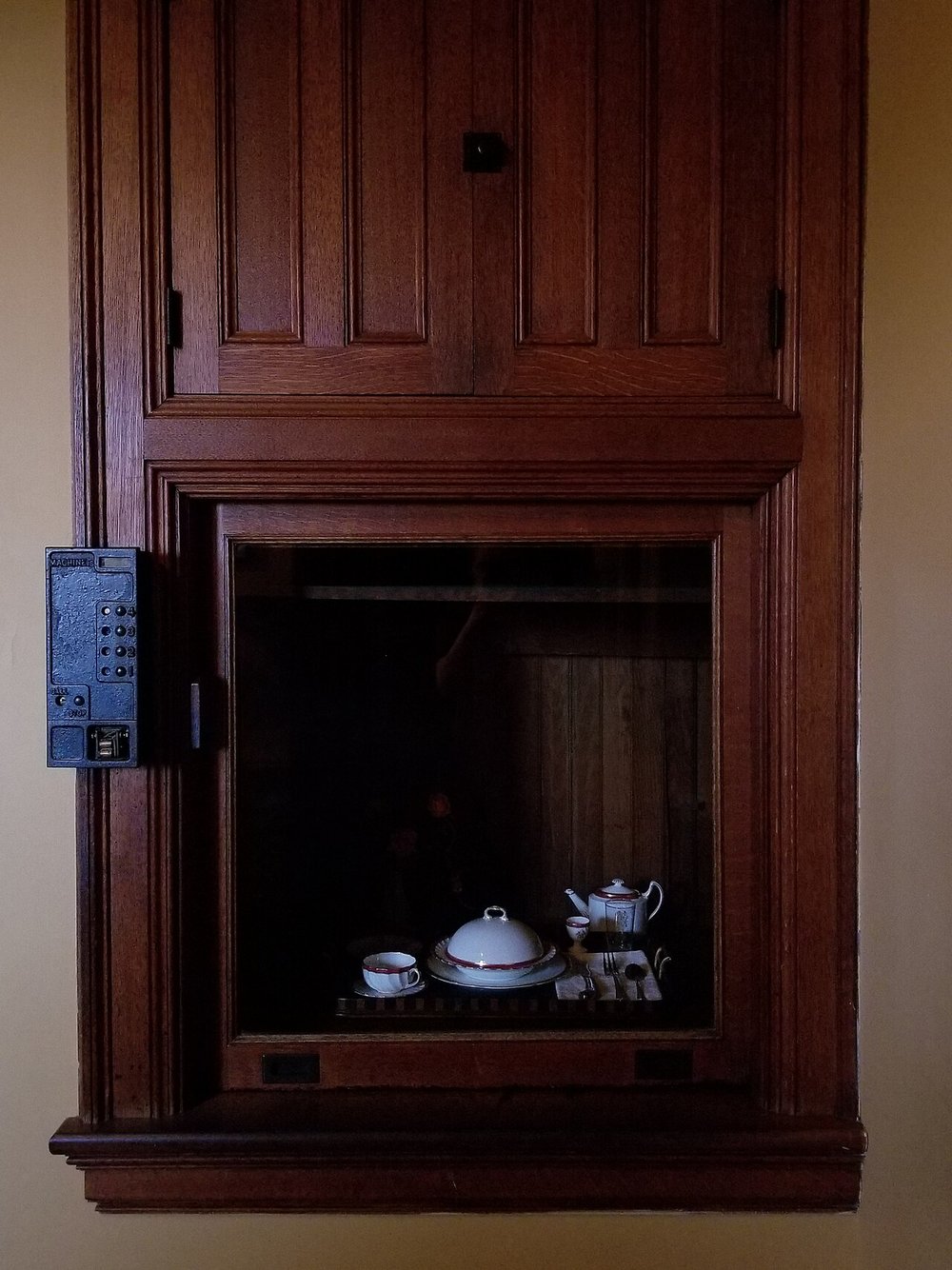 A wood-panelled dumbwaiter holding a tray of china in the pantry of Biltmore House