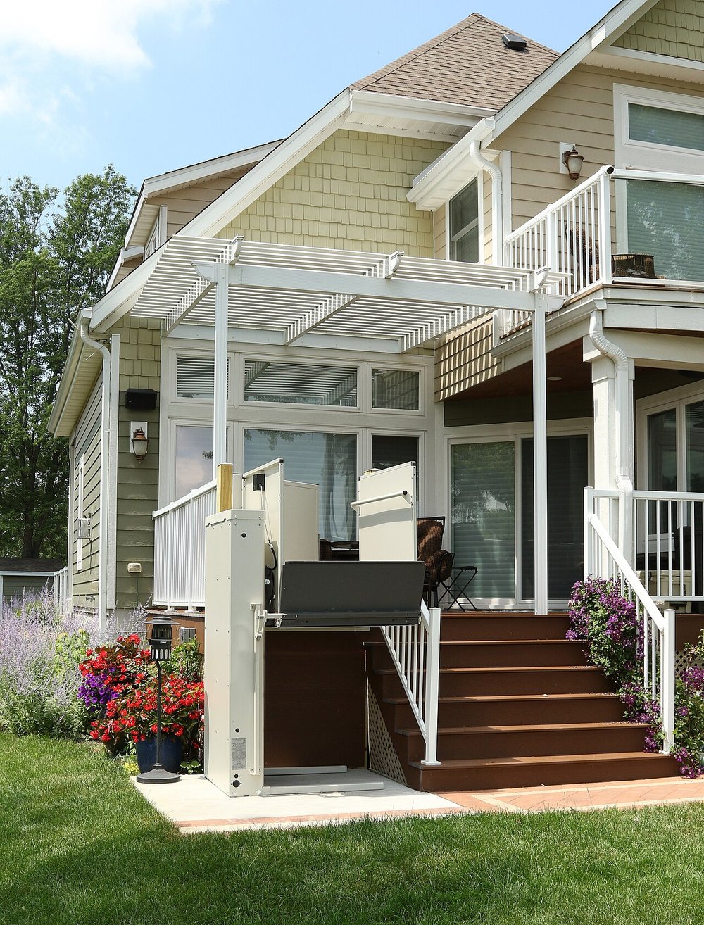 A vertical platform lift beside the front steps and porch of a two-storey house